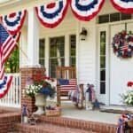 Patriotic front porch decorated with American flags, wreaths, and red, white, and blue accents for I.